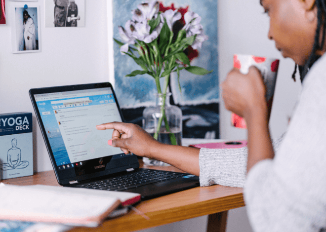 Person browsing emails on a laptop while holding a cup of coffee.