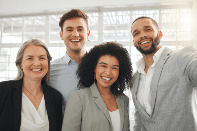 A diverse group of four professionals smiling together, suggesting a friendly and inclusive work environment.