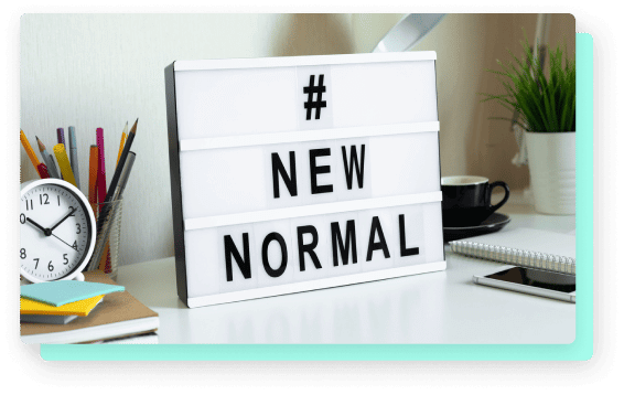 A desk with a lightbox reading "#NEW NORMAL," surrounded by stationery, a clock, and a coffee cup.